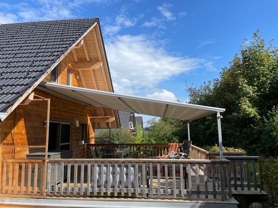 Holzterasse auf Südseite mit Markise und Zugang zum Garten