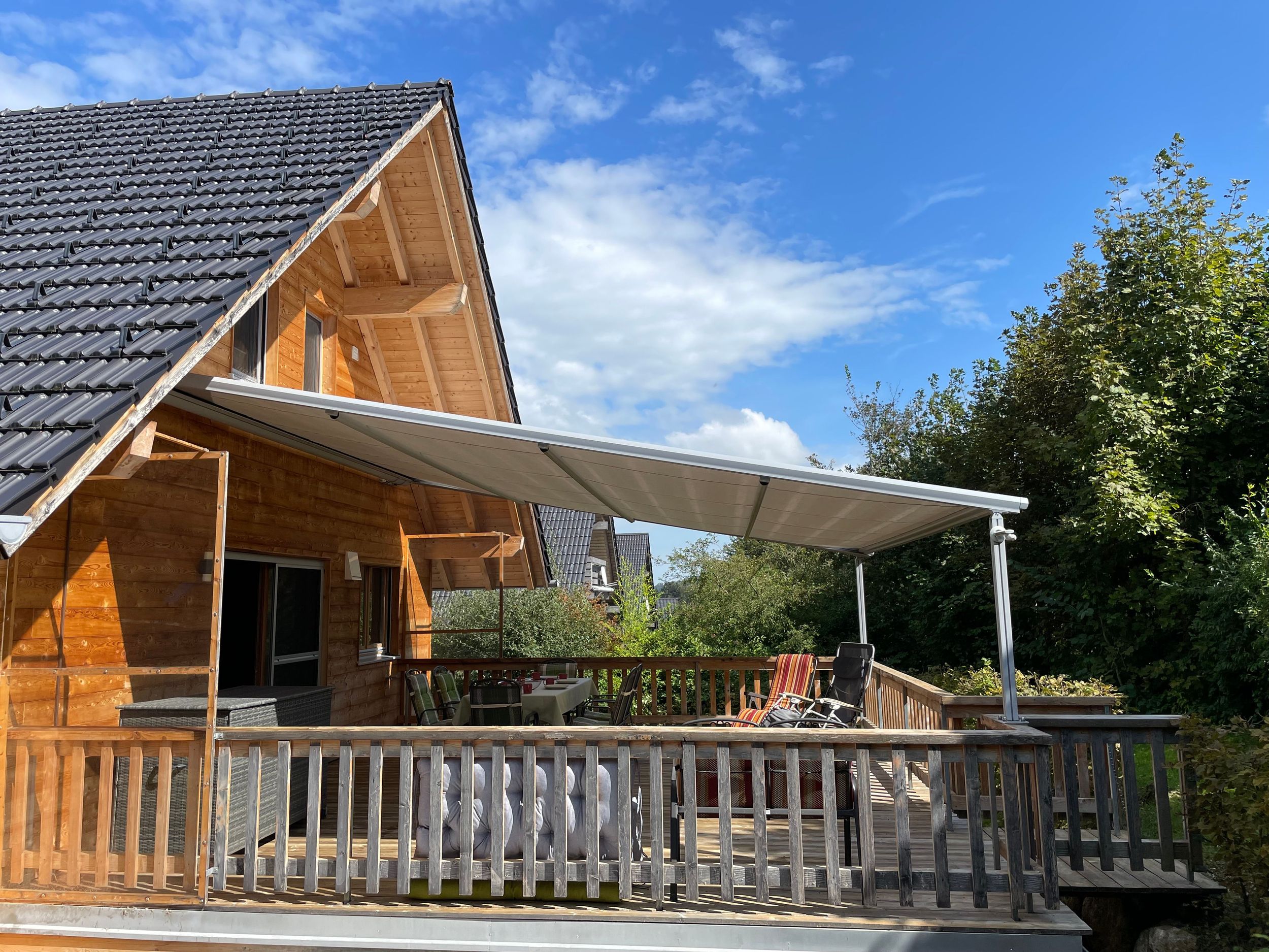 Holzterasse auf Südseite mit Markise und Zugang zum Garten